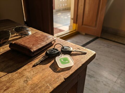 Motorcycle keys with lessworry tag on table beside wallet and sunglasses